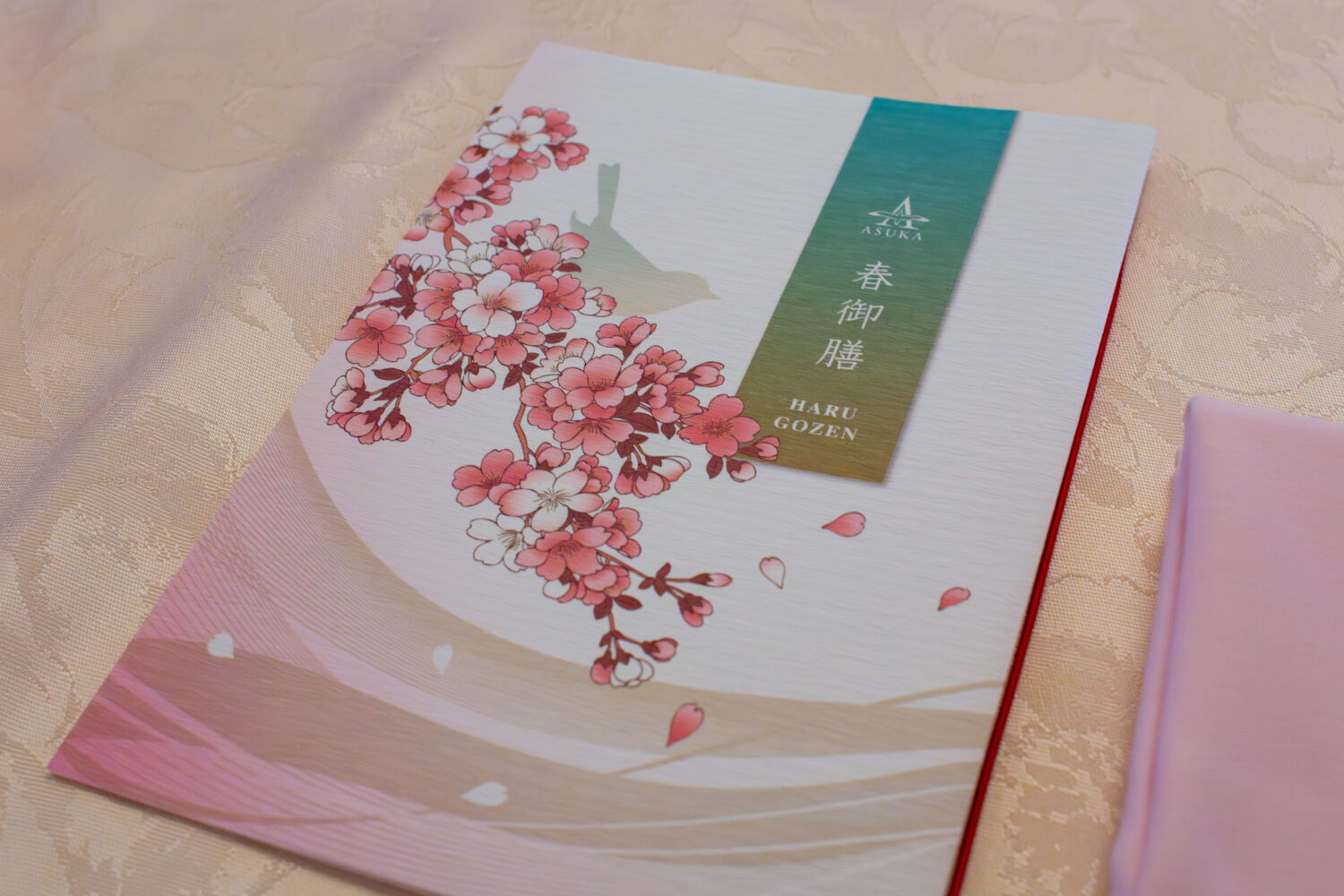 満開の桜が描かれた春御膳のメニュー。テーブルクロスとナプキンも桜色